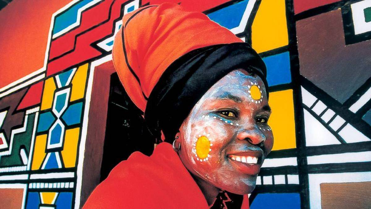 Ndebele-Frau vor typischer Hausbemalung | © Chamäleon Ndebele-Frau vor typischer Hausbemalung | © Chamäleon
